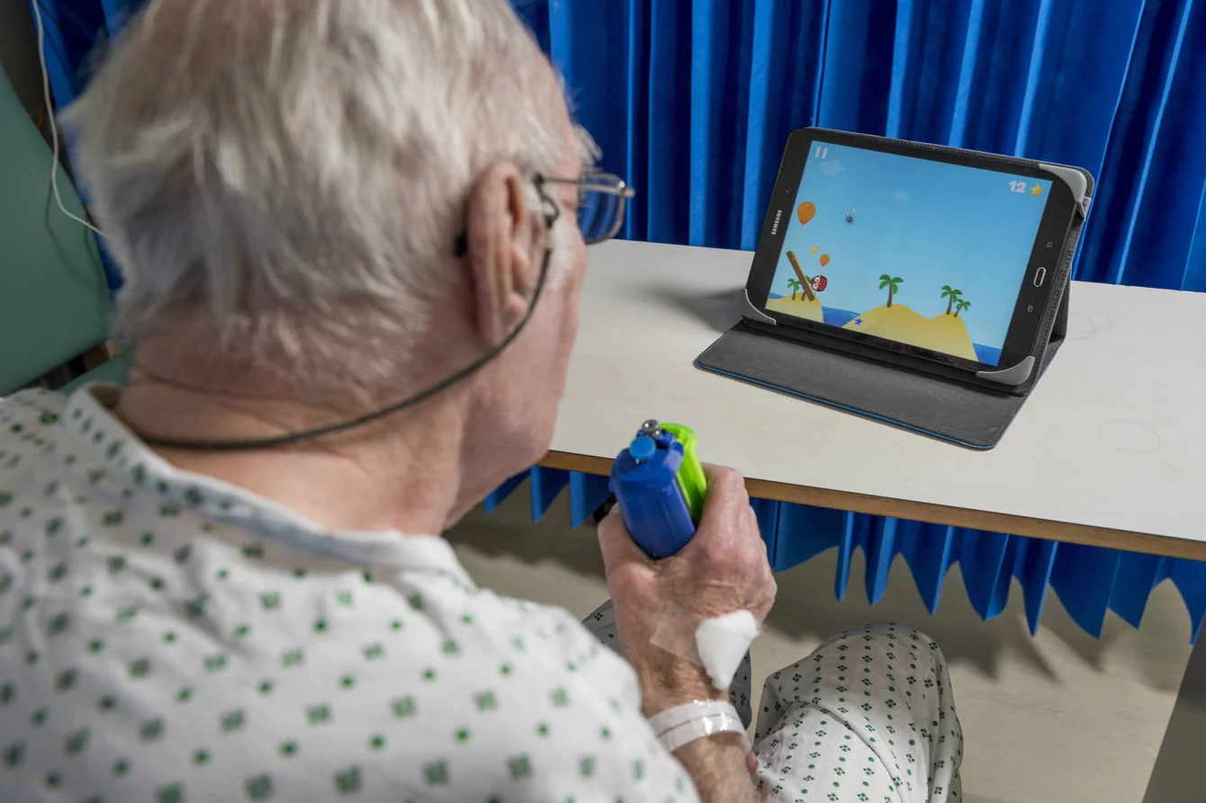 Elderly man using a game for rehabilitation