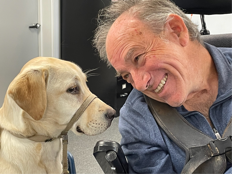 IMG_1753_web Man smiling next to a service dog