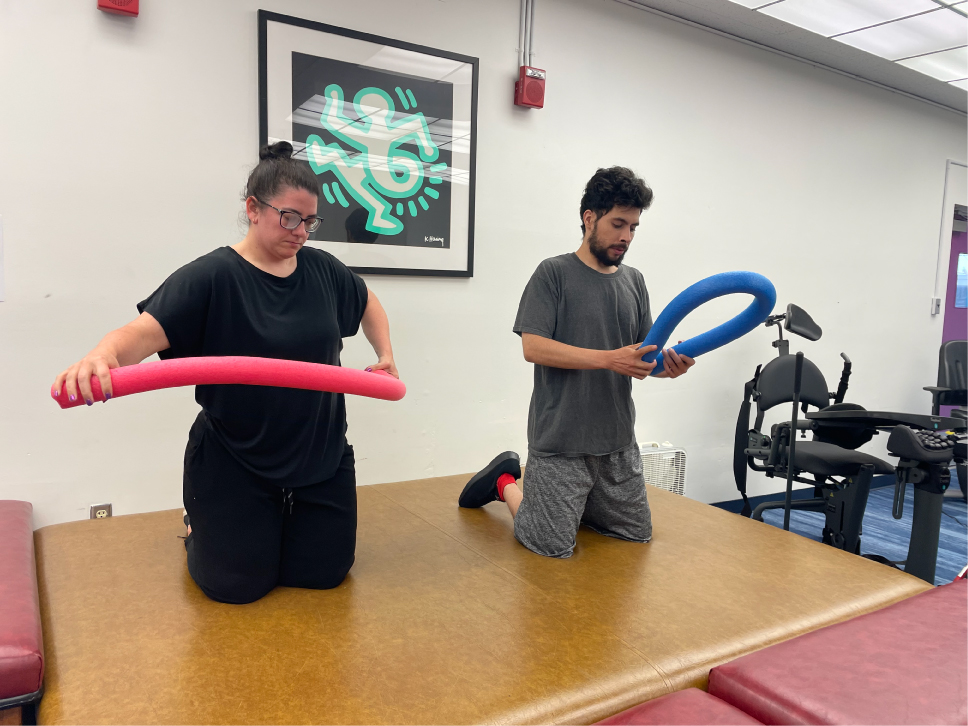 2 people bending a pool noodle in Daily Living Skills Class