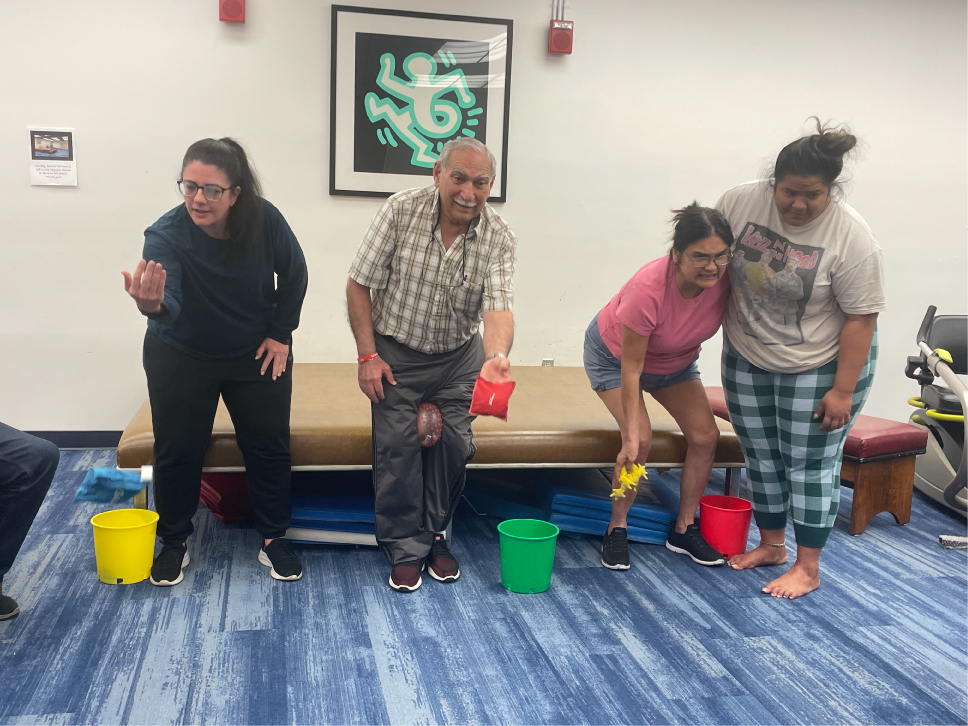 Group of 4 people tossing small bean bags during a mobility and fitness class